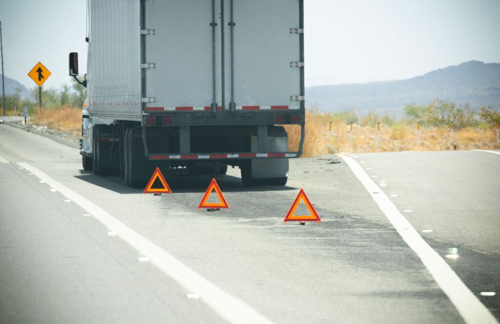 A Diesel Truck broke down on the side of the road with caution cones