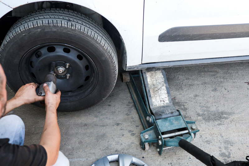 Auto Technician changing a tire on a fleet Van